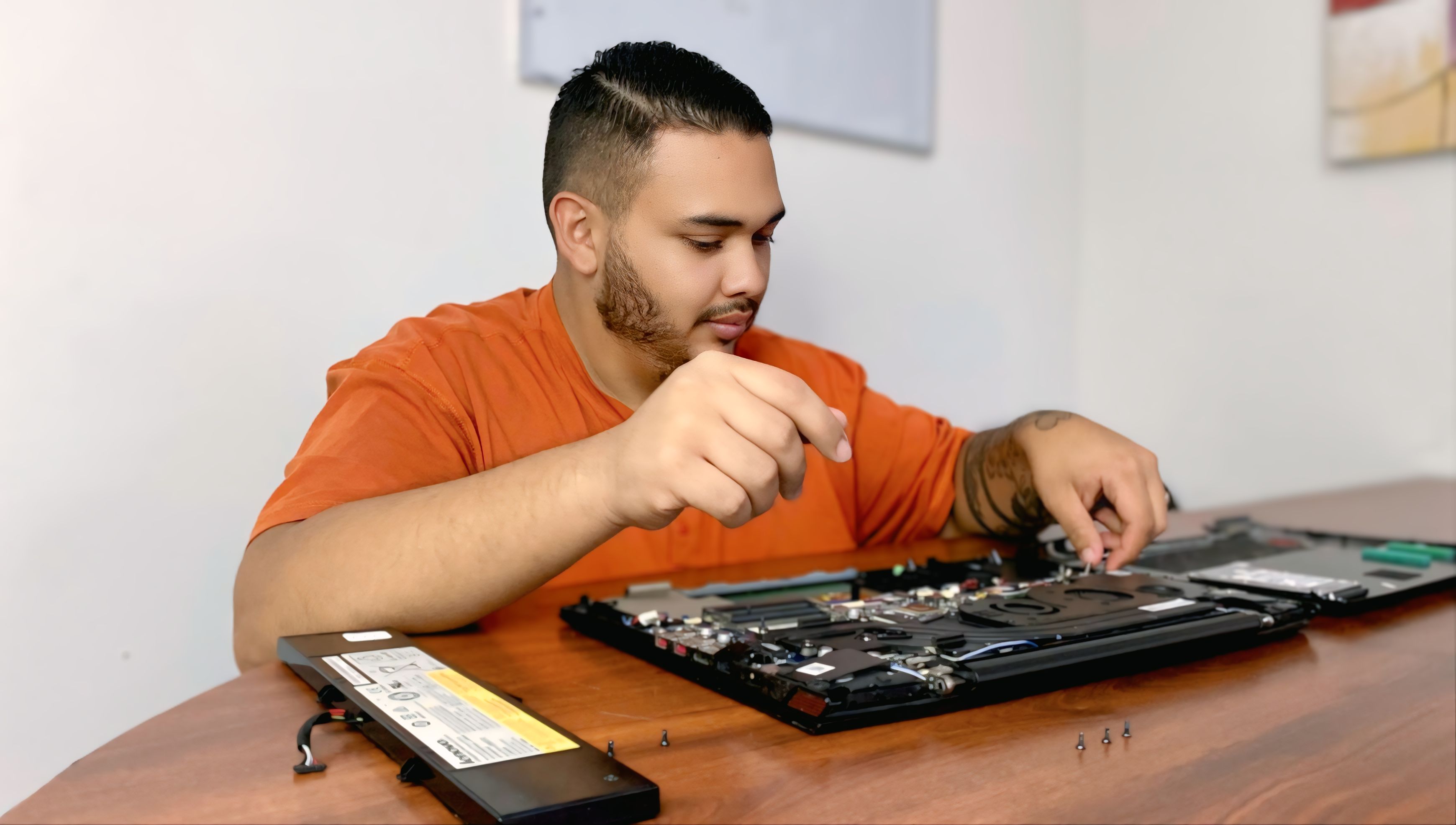 Experto en soporte técnico de Magna IT Solutions realizando mantenimiento a una laptop: limpieza de ventilación y reemplazo de piezas.